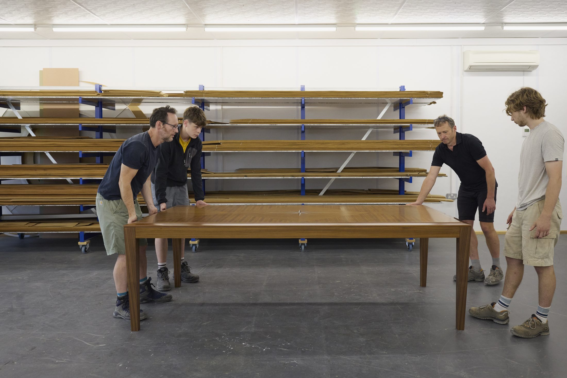 Workshop team carrying a finished dining table with star inlay